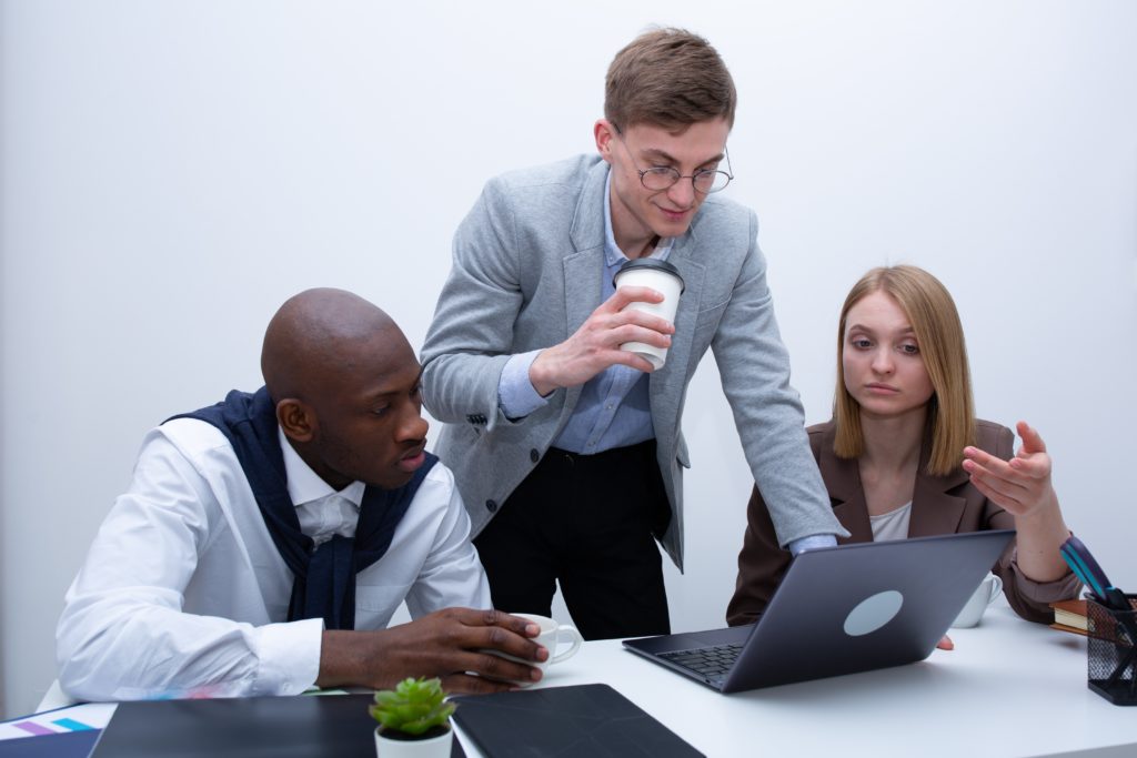 Team members discussing something in front of a laptop