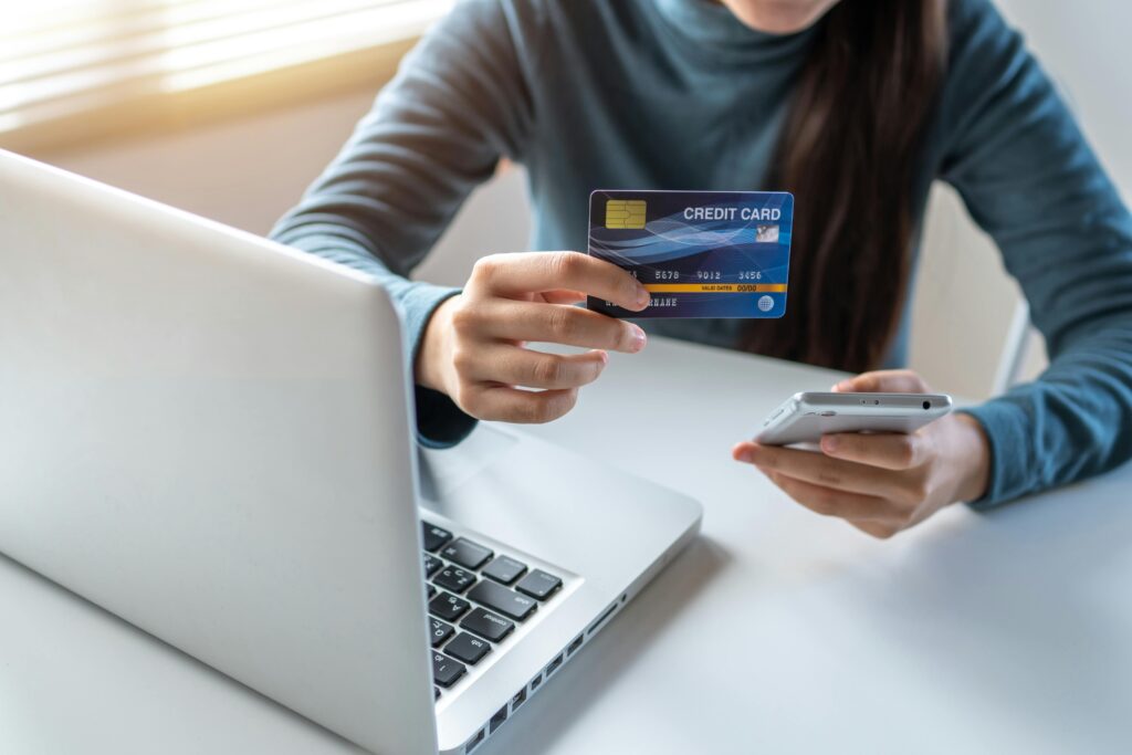 Man holding a credit card in front of a laptop