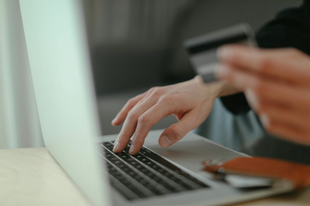 Someone typing on a laptop while holding their credit card