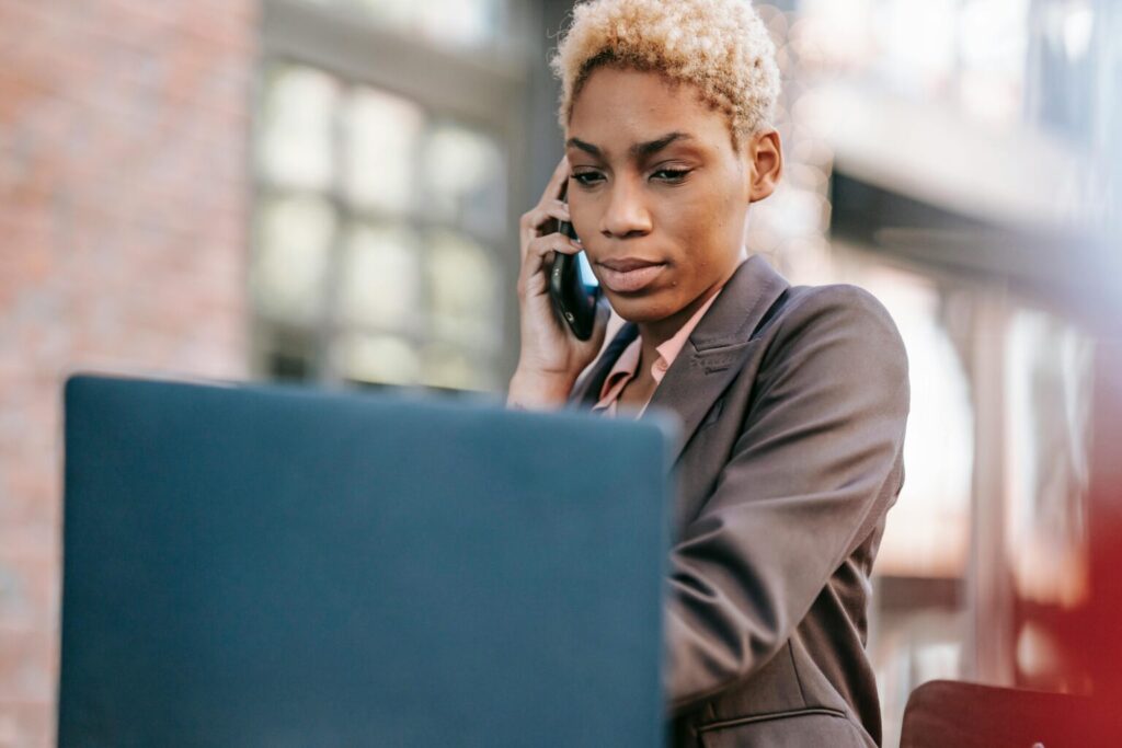 Woman talking to someone over the phone in front of her laptop