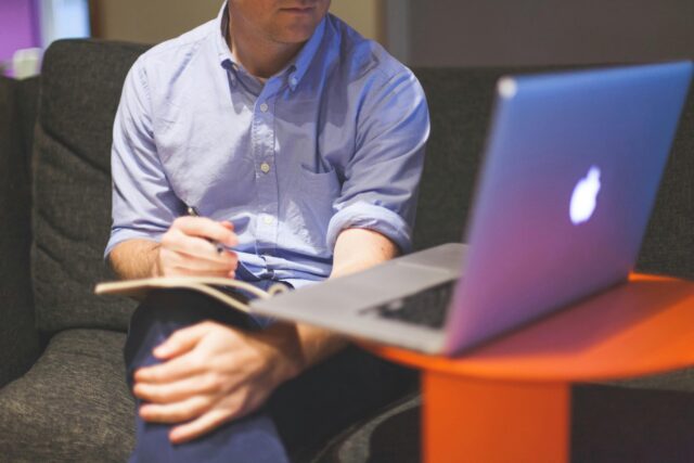 A man sitting while looking at something on his laptop